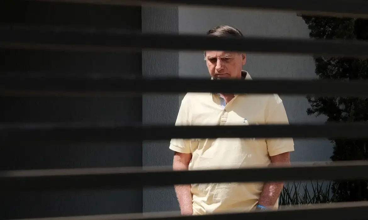 Reuters/Diego Herculano/Arquivo/Proibida reprodução Brazil's former President Jair Bolsonaro stands at his home while under house arrest, amid the final phase of his trial, accused of plotting a coup after his electoral defeat, in Brasilia, Brazil, September 3, 2025. REUTERS/Diego Herculano REFILE - CORRECTING DATE FROM